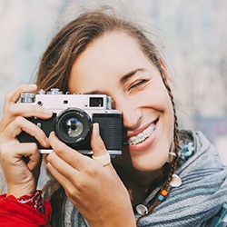 Girl with traditional orthodontics taking pictures with camera