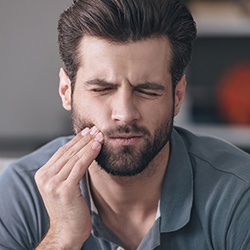 Man with tooth pain holding cheek before root canal therapy