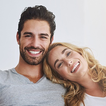 Couple leaning against each other smiling after receiving advanced dental services and technology