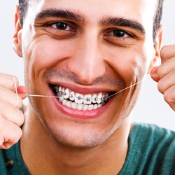 Smiling man flossing between his braces in McKinney