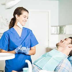 Smiling dental assistant talking to patient relaxing in treatment chair