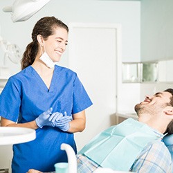 Smiling dental assistant talking to patient relaxing in treatment chair