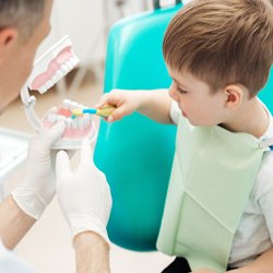 Boy practicing brushing teeth during children's dentistry visit