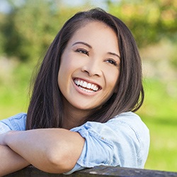 Lady leaning on wooden rail smiling after dental bonding