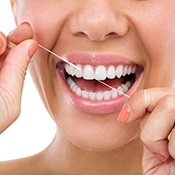 A woman flossing to prevent dental emergencies