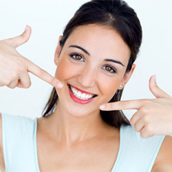 A woman pointing at her smile after tooth colored fillings
