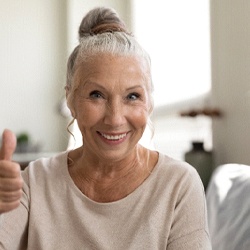 Woman gives thumbs-up after full mouth reconstruction in McKinney