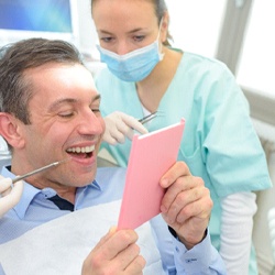 Man admiring his smile after full mouth reconstruction in McKinney