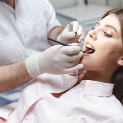 A dentist using specialized dental instruments to perform a dental checkup on a female patient