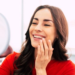 : A woman admiring her dental implants in a hand mirror