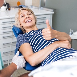 Woman smiling in the dental chair giving thumbs up