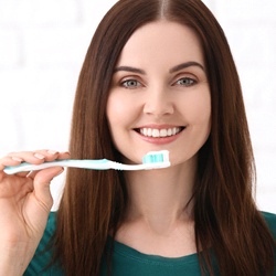 Woman who is smiling while brushing her teeth