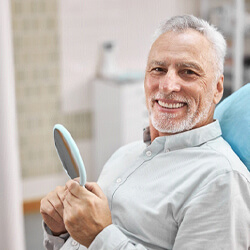 Senior man with dental implant supported denture smiling in the dental chair