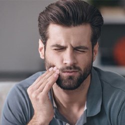 Man with mouth pain, possibly experiencing dental implant failure