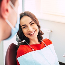 Woman smiling at her dentist during dental implant tooth replacement visit