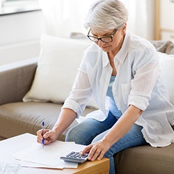 Woman typing on a calculator to estimate the cost of dental implants