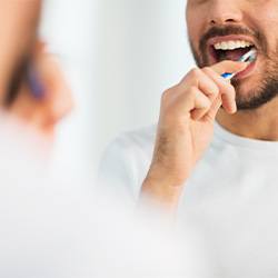 Man smiling while brushing his teeth