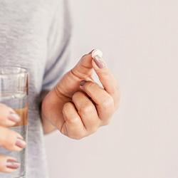 Woman holding a pill and water