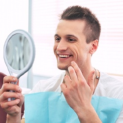 Dental patient checking smile in the mirror after emergency dentistry
