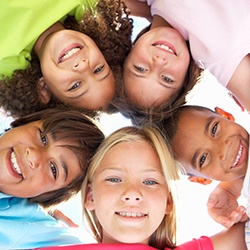 Group of children huddled together and smiling after children's dentistry visit