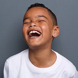 Young boy in white shirt with dental sealants smiling
