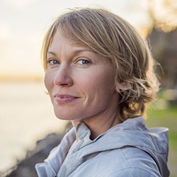 Blonde woman smiling at sunset after tooth extractions