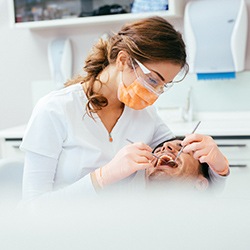 Dentist performing dental examination on patient under I V dental sedation