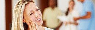 Woman in pain holding face before emergency dentistry