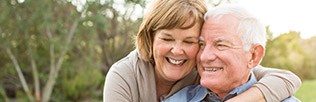 Laughing senior couple outdoors after restorative dentistry