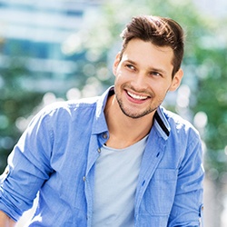 Closeup of man with white, straight teeth after porcelain veneers smiling outside