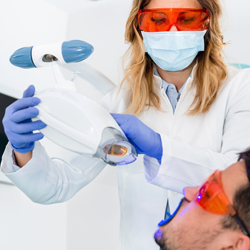 Dentist performing Zoom teeth whitening on male patient
