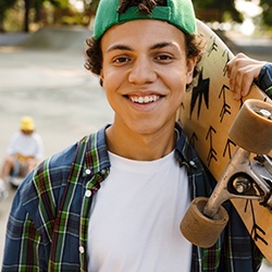 a smiling teen holding a skateboard