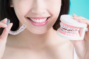 girl holding invisalign and braces