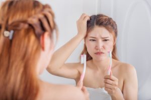 Concerned woman with bad brushing habits looks at her toothbrush