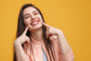 Woman pointing to her smile after completing Invisalign.