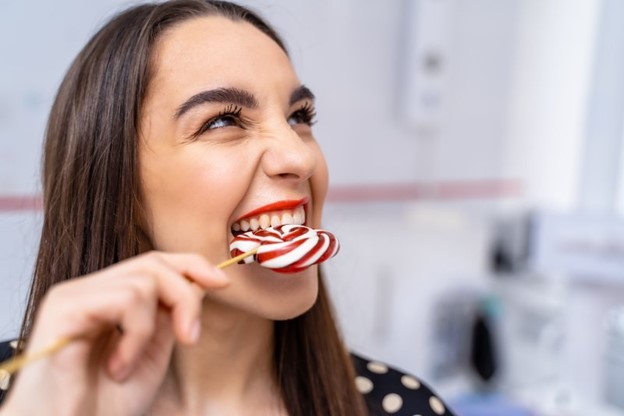 Woman biting into a lollipop.