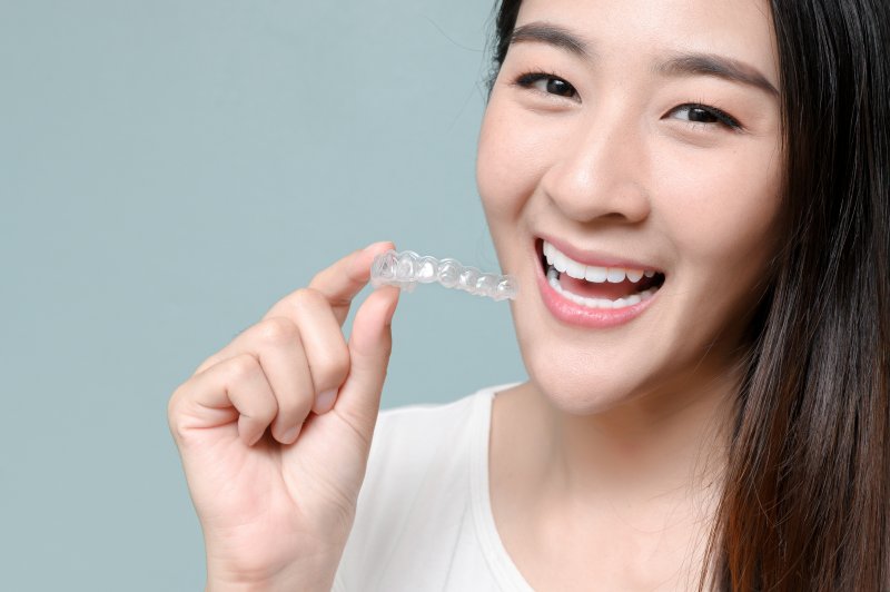 smiling person holding an Invisalign aligner