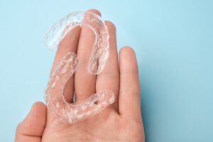 Hand shown holding clear aligners.