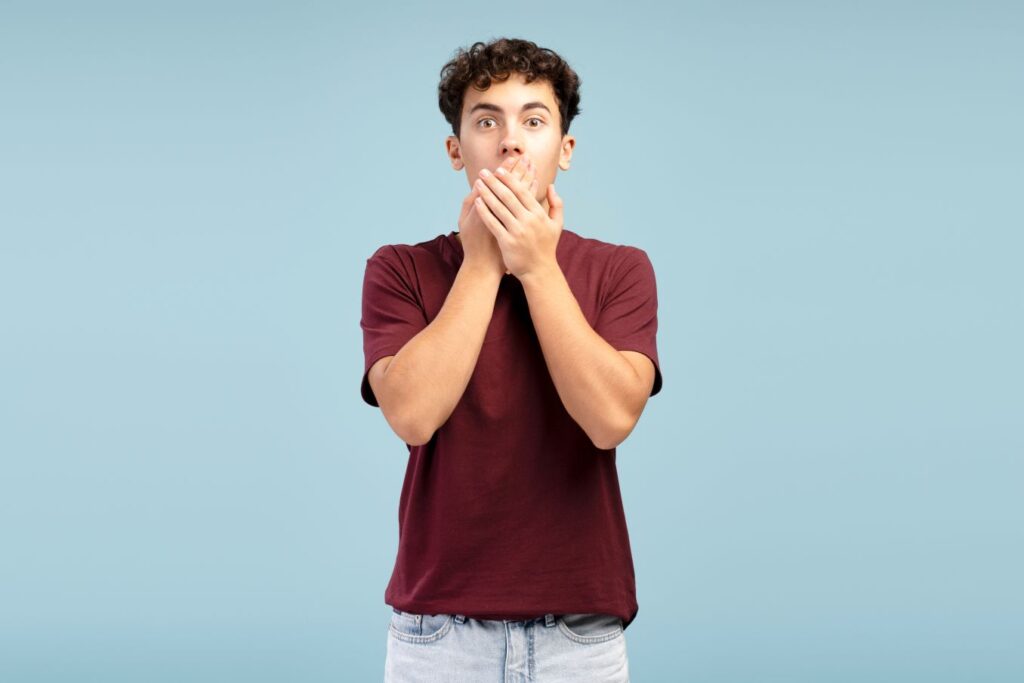 A teenage boy covering his mouth with his hands